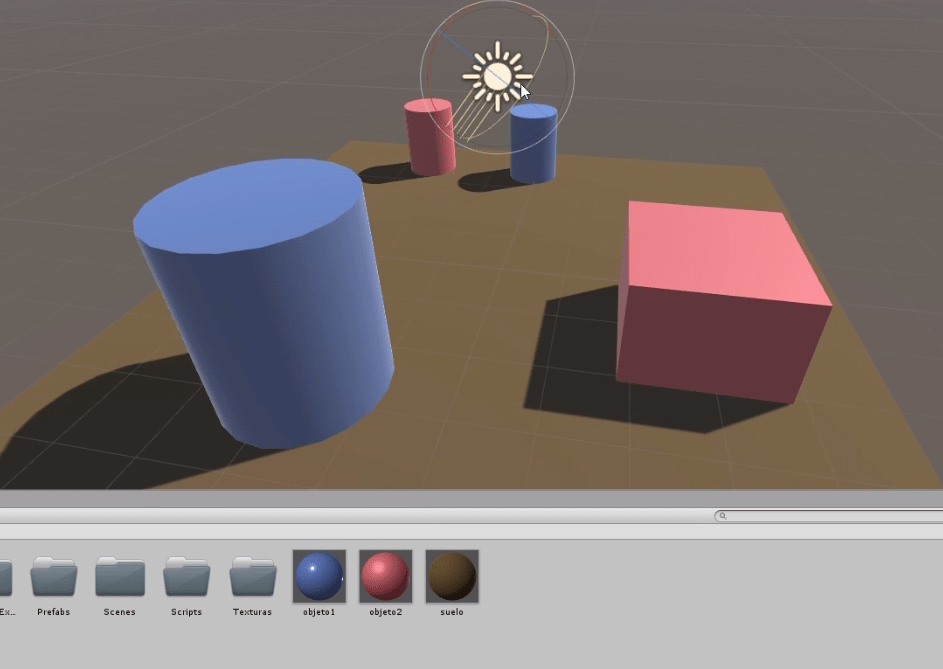 programa unity3d se observa una escena con un plano, un cubo y dos cilindros. El plano está pintado color marrón, hay dos cilindros azules, uno rojo y un cubo rojo, Además una fuente de luz direccional.